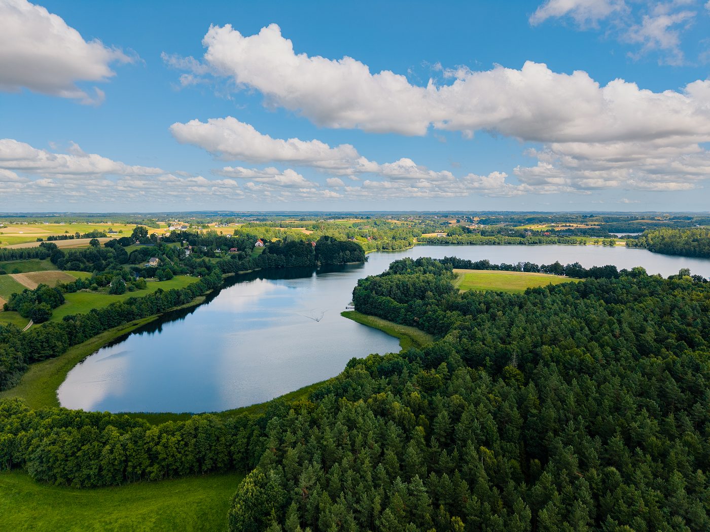 Jezioro Białe z lotu ptaka — tafla wody otoczona lasem, w tle pola i rozproszona zabudowa